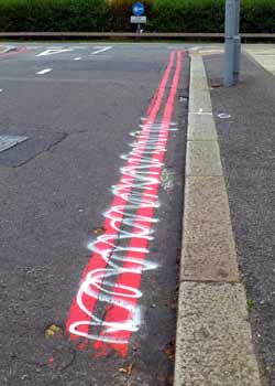 Partially crossed-out red route road markings.