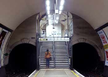 Northern line tunnel mouths at steps at station with a narrow platform.