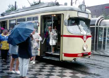 Lady having difficulty descending steps on an older tramcar.