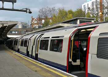 Piccadilly line in front of District line train at Ealing Common station.