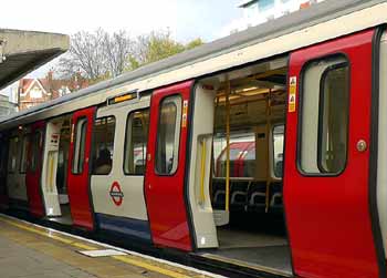 District line in front of Piccadilly line train at Ealing Common station.