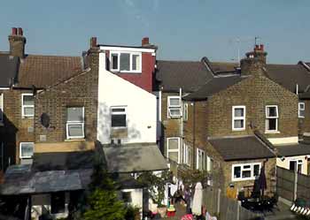 Train window view of terraced house backs.